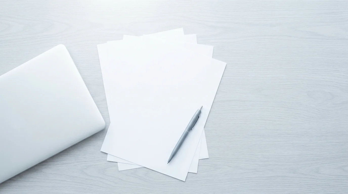 Aufgefächerte Papierunterlagen neben einem Laptop an einem aufgeräumten Arbeitsplatz